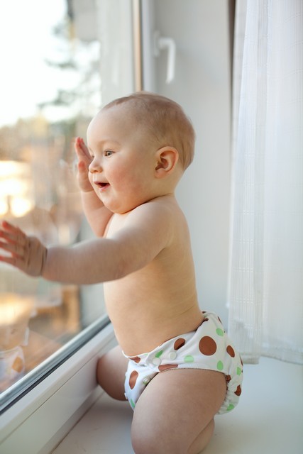 happy baby boy looks through the window